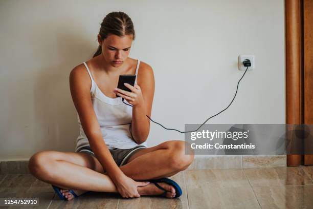 teenage girl sitting on floor and using phone - smartphone addiction stock pictures, royalty-free photos & images