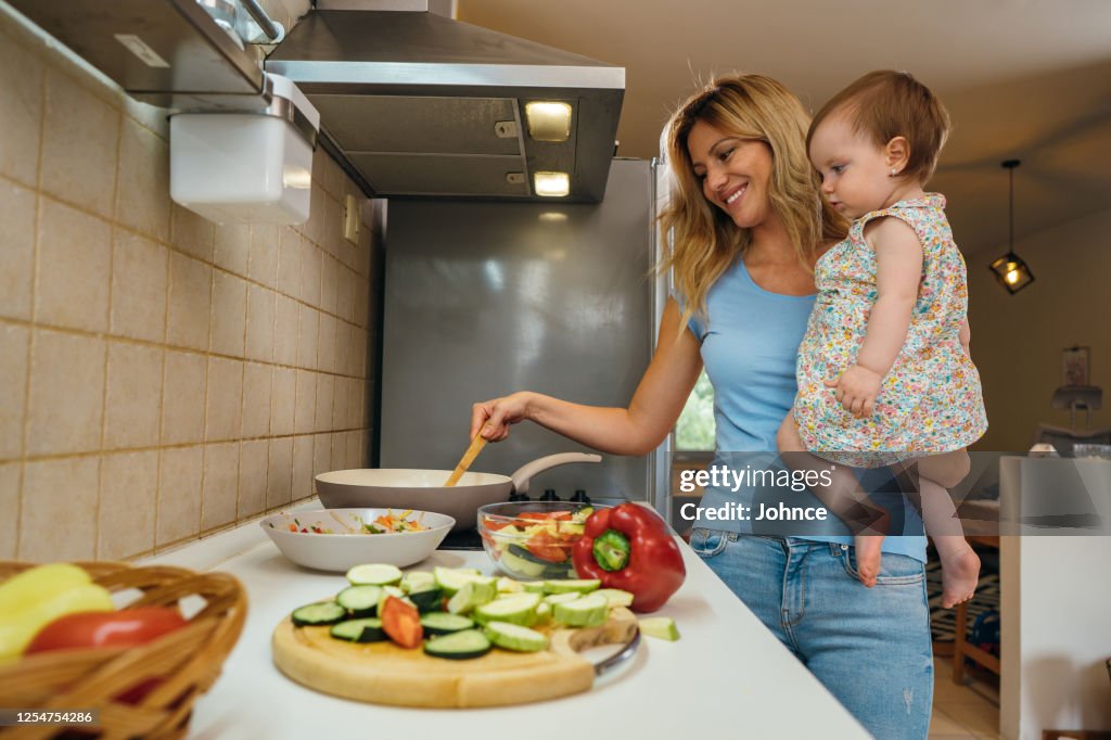 Cooking With Baby Mother Cooking With Baby In Arms High-Res Stock Photo - Getty Images
