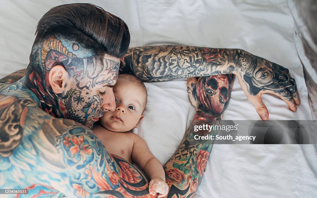 Father With Whole Body Covered In Tattoos Lying With His Baby Son On Bed In  Bedroom High-Res Stock Photo - Getty Images