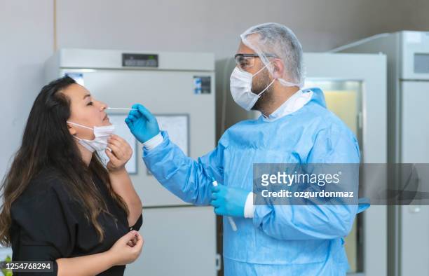 male doctor in protective suits taking swab test from a female patient in hospital - forensic stock pictures, royalty-free photos & images