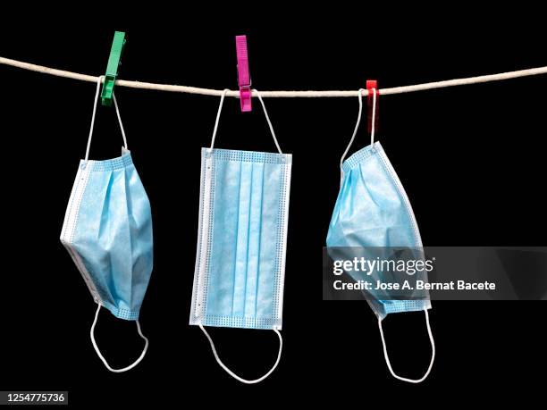 blue medical face mask hanging at clothesline against on a black background. - 風邪マスク ストックフォトと画像