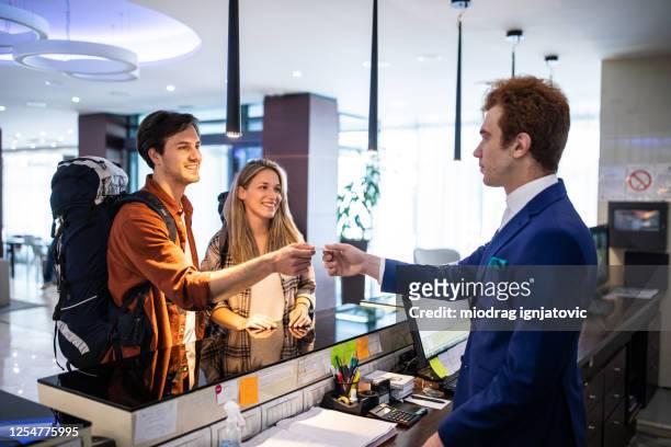 receptionist assisting guests to check in at luxury hotel - id badge stock pictures, royalty-free photos & images