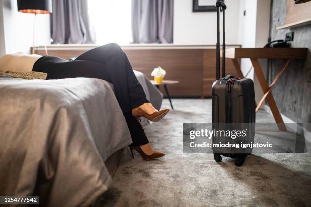 femme d’affaires avec des talons hauts relaxant à la suite d’hôtel - suite photos et images de collection