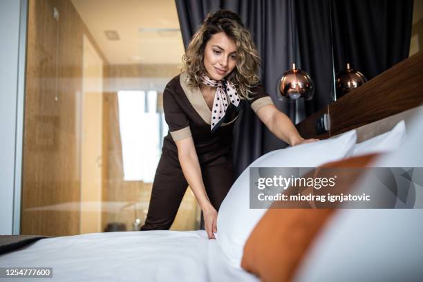 cameriera in uniforme che prepara la suite dell'hotel per il prossimo ospite - albergo di lusso foto e immagini stock