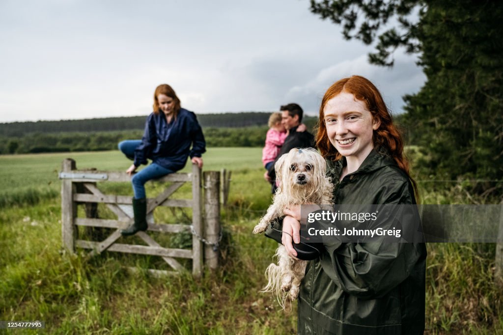 Smiling teenage girl and wet dog on weekend hike with family