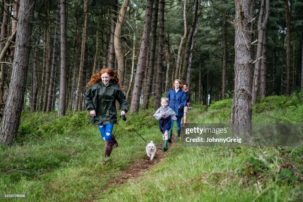 Teenage girl and dog leading family on hike through forest