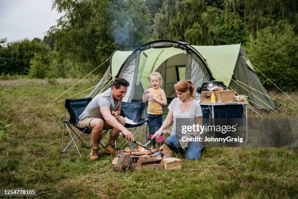 familie met één kind dat over open brand op het kamperen reis kookt - the tent stockfoto's en -beelden