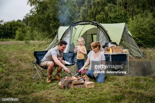 familj med ett barn matlagning över öppen eld på campingresa - camping family bildbanksfoton och bilder