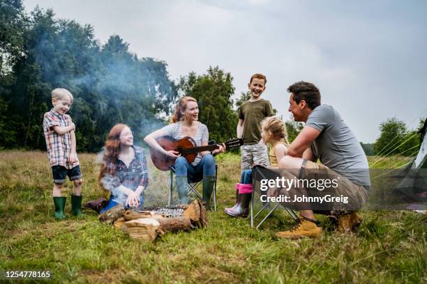 familie genießt mutter spielen gitarre während camping-reise - child singing stock-fotos und bilder