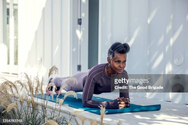 woman in plank position on exercise mat - postura de plancha fotografías e imágenes de stock
