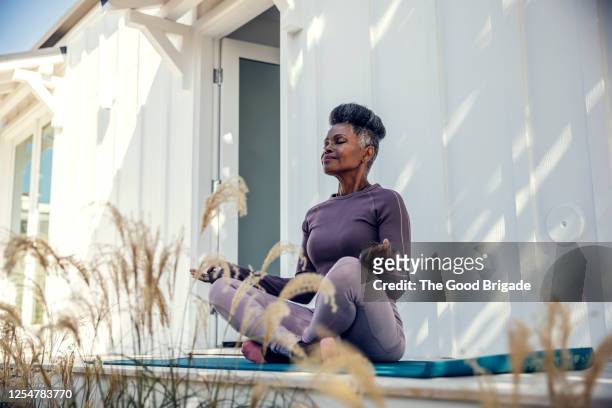 mature woman meditating in backyard - benessere foto e immagini stock