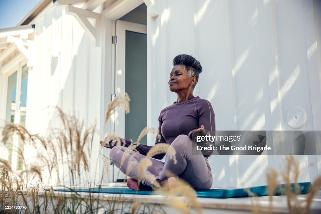 Mature woman meditating in backyard