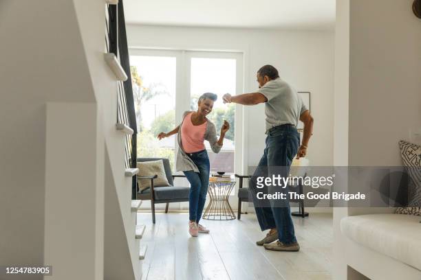 mature couple dancing in living room - stili di vita foto e immagini stock