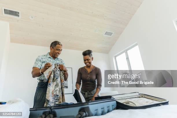 happy couple packing suitcase for vacation - making choice stock pictures, royalty-free photos & images