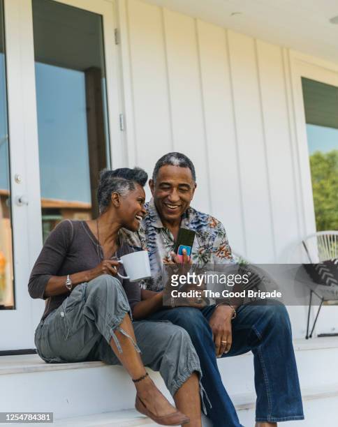 mature couple drinking coffee on porch - sunny morning stock pictures, royalty-free photos & images