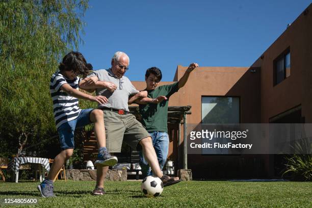 skilled grandfather dribbling around his grandsons - senior kicking stock pictures, royalty-free photos & images