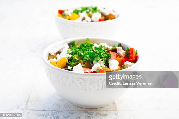 two bowl of grilled eggplant and bell peppers with goat cheese and parsley - salad bowl stock pictures, royalty-free photos & images