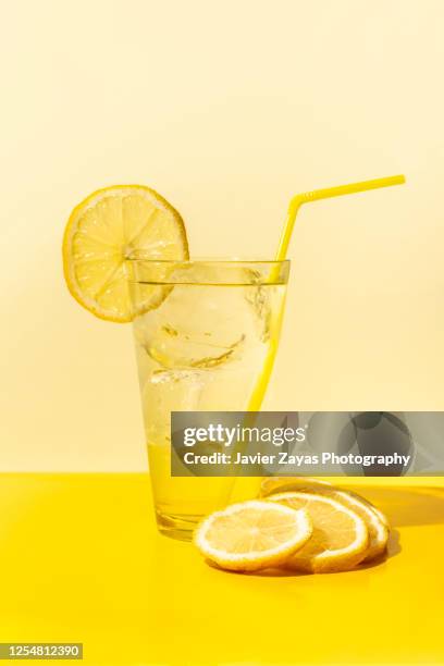 ice cold lemonade glass on yellow colored table - citroen frisdrank stockfoto's en -beelden