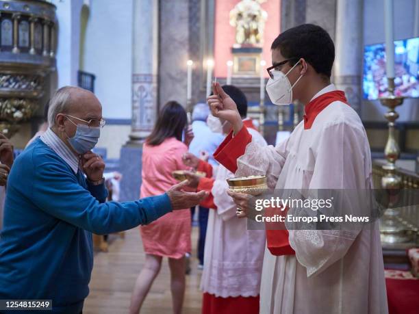 An altar server is seen giving communion during a mass in honor of San Fermín during his festivity on what would be the second day of the festivals...