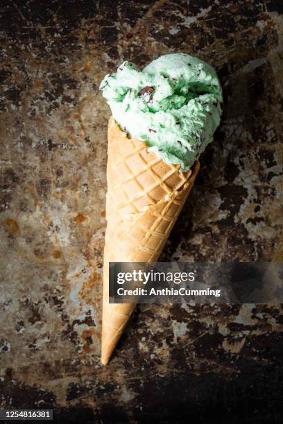 mint choc chip ice cream cone on rusty background - mint ice cream stock pictures, royalty-free photos & images