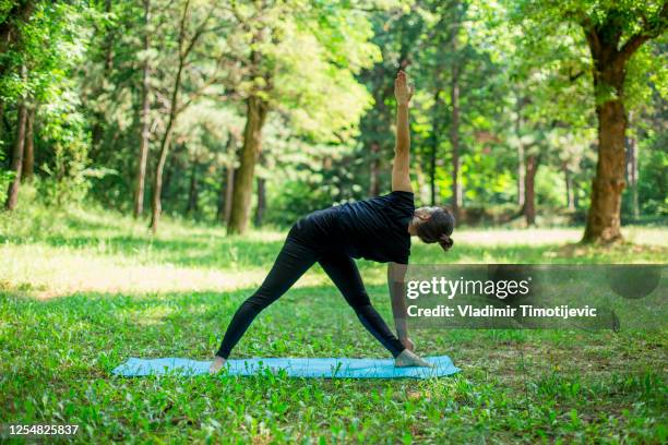 yoga practice in the nature - parivrtta trikonasana stock pictures, royalty-free photos & images