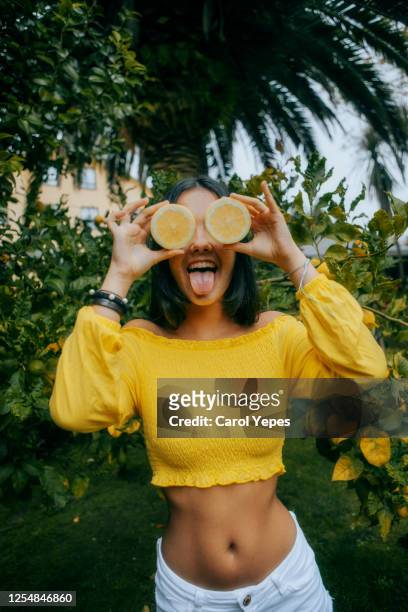 young female with lemon in front of eyes.outdoors - lemon fruit stock pictures, royalty-free photos & images