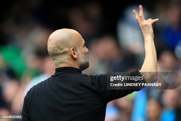 Manchester City's Spanish manager Pep Guardiola shows two fingers for the last two football match of the English premier League at the end of the...