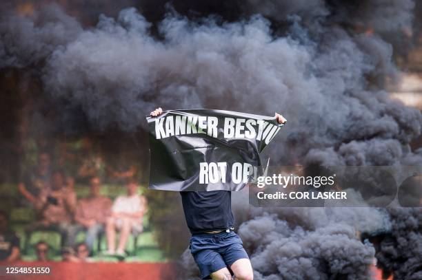 Supporter holding a banner reading "cancer board rotten" storms the field during the Dutch Premier league football match between FC Groningen and...