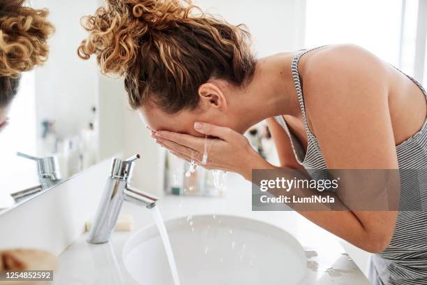 bacteriën hoort in de afvoer niet op je gezicht - woman washing face stockfoto's en -beelden