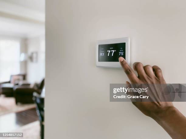 woman adjusts thermostat - cold temperature inside home stock pictures, royalty-free photos & images