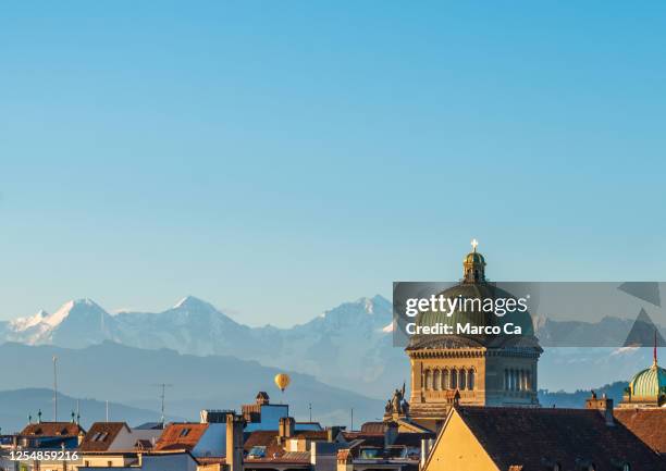 nahansicht der kuppel des bundeshauses, des schweizer regierungsgebäudes in bern und der schweizer hochalpen im hintergrund bei sonnenaufgang - bern stock-fotos und bilder