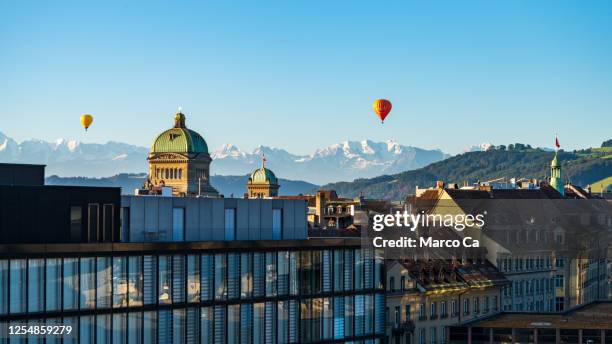 view of the dome of the bundeshaus, the swiss government building, the church of the holy spirit in bern and the swiss high alps in the background at sunrise - bern canton stock pictures, royalty-free photos & images