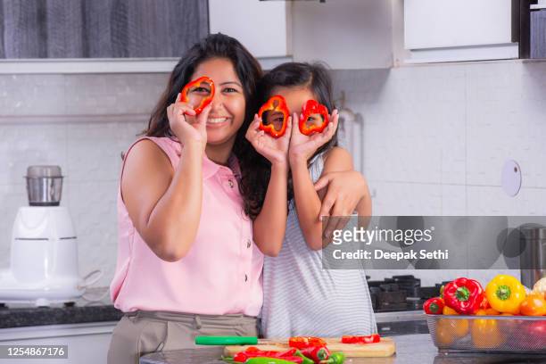 mamá e hija jugando con rodajas de pimienta foto de stock - mom flirting fotografías e imágenes de stock