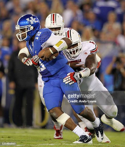 Morgan Newton#12 of the Kentucky Wildcats is sacked by Greg Scruggs of the Louisville Cardinals during the game at Commonwealth Stadium on September...