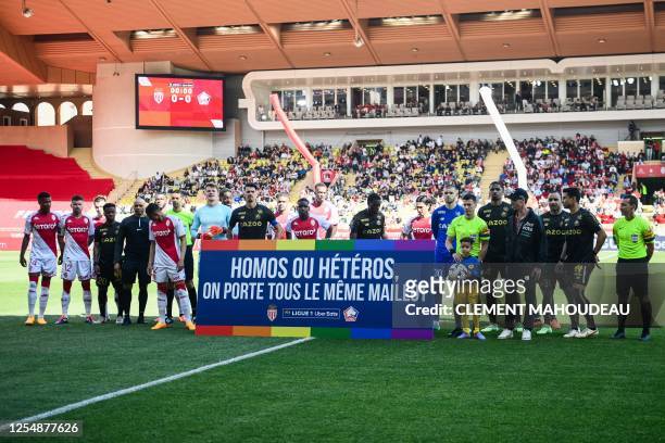 Players of AS Monaco and Lille Olympique Sporting Club stand with a rainbow LGBTQIA+ coloured placard reading "Gay or straight, we all wear the same...