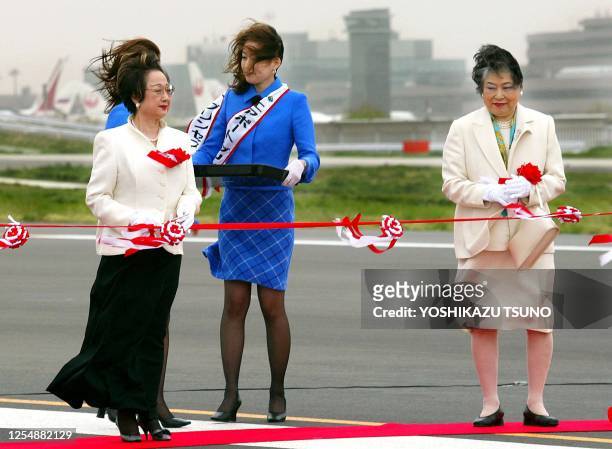 While in the strong wind, Japanese Land and Transport Ministrer Chikage Ohgi and Chiba Governor Akiko Domoto prepare to cut the ribbon for the...