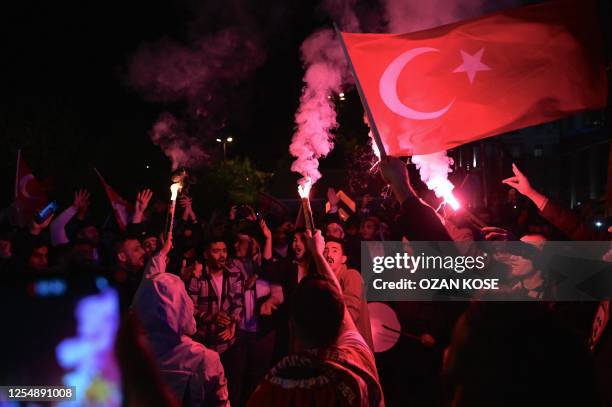 Supporters of Turkish President light flares as they celebrate in front of the Justice and development Party headquarters after polls closed in...