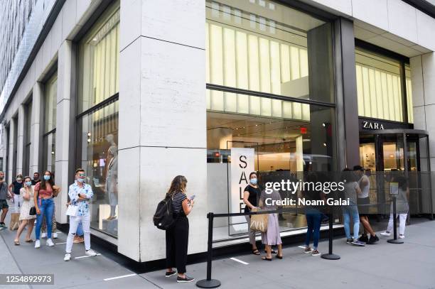 People stand in line outside the Zara store on Fifth Avenue as New York City moves into Phase 3 of re-opening following restrictions imposed to curb...