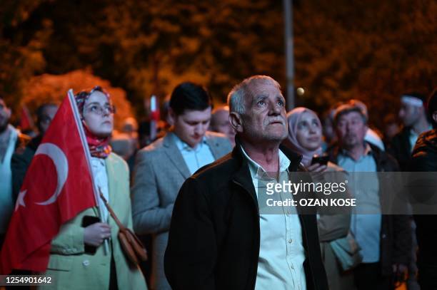 Supporters of Turkish President look at early presidential election results displayed on a screen in front of the Justice and development Party...