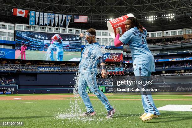 Vladimir Guerrero Jr. #27 of the Toronto Blue Jays gives an ice bath to teammate Danny Jansen during his post-game interview after Jansen hit a...