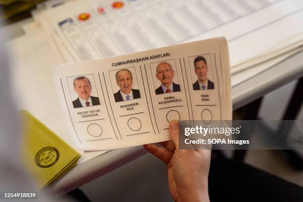 An election official displays a voting card with the faces of candidates during the election at Saffet Çebi school polling station. 64 millions...