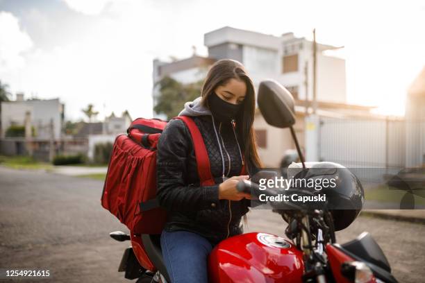 delivery biker checking phone- motogirl, motoboy - motoboy stock pictures, royalty-free photos & images