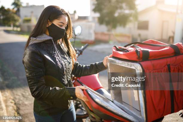 delivery biker open his delivery backpack- motogirl, motoboy - motoboy stock pictures, royalty-free photos & images