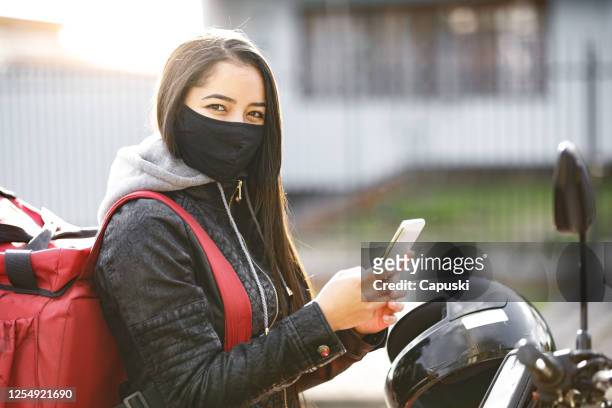 delivery biker holding phone- motogirl, motoboy - motoboy stock pictures, royalty-free photos & images