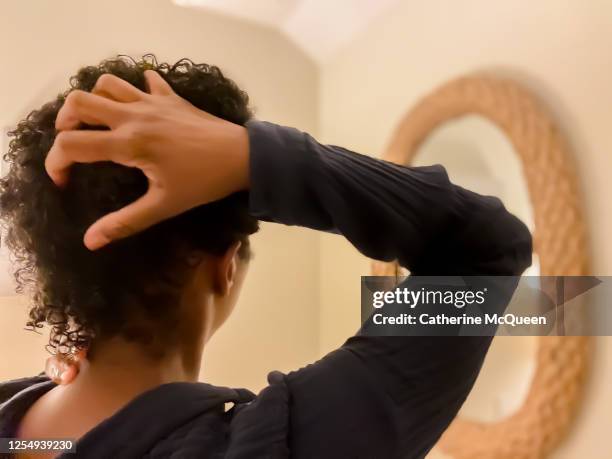 mid adult african-american woman runs fingers through wet natural hair - flat iron stock pictures, royalty-free photos & images