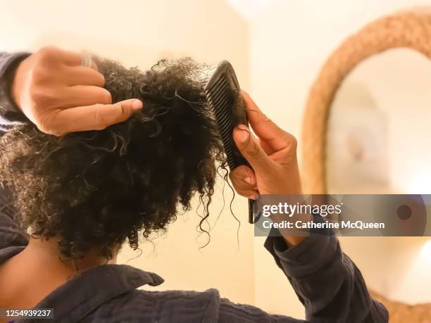 mid adult african-american woman detangles wet natural hair with comb - naturligt hår bildbanksfoton och bilder