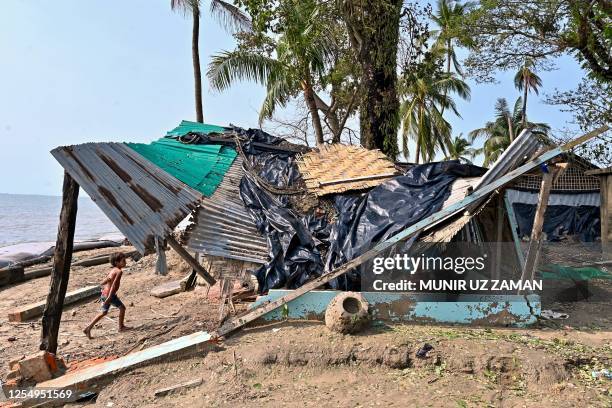 Boy walks beside a house which was partially destroyed by cyclone Mocha, in Shahpori island on the outskirts of Teknaf on May 15, 2023. Cyclone Mocha...