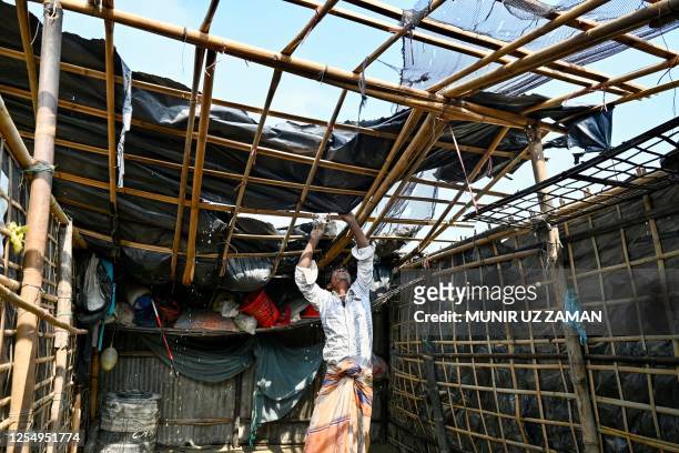 Man fixes his house's roof which was destroyed by cyclone Mocha, in Shahpori island on the outskirts of Teknaf on May 15, 2023. Cyclone Mocha crashed...