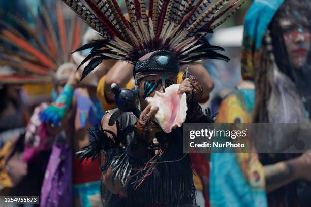 Pre-Hispanic dancer holds a snail during a procession on the occasion of the Toxcatl Ceremony in the Zocalo of Mexico City, which represents one of...