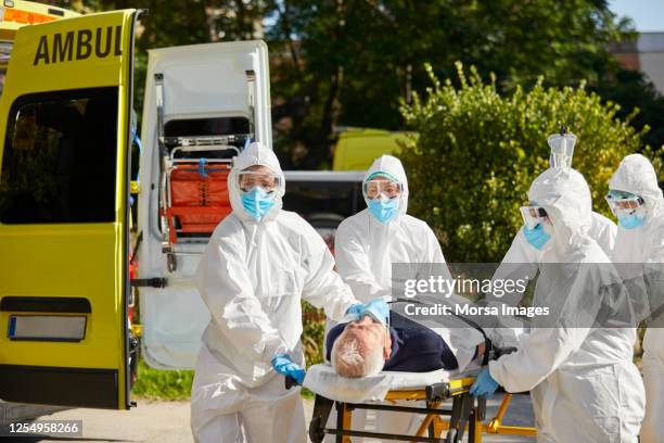 emergency healthcare workers with covid-19 patient - coveralls stock pictures, royalty-free photos & images